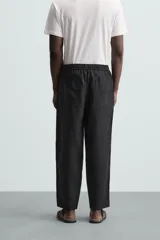 Pantalón negro de lino, corte recto y relaxed fit, con cintura elástica ajustable con cordón, bolsillos laterales y traseros.