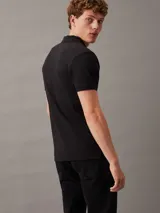 Chomba negra de piqué de algodón elástico, corte regular, con cuello clásico, tapeta de dos botones y logo bordado de Calvin Klein en el pecho.