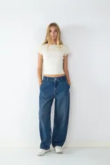 Pantalón jean azul oscuro de corte ancho, estilo skater, con cierre de cremallera y botón, y cuatro bolsillos.