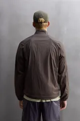Cazadora relaxed fit confeccionada en tejido técnico ligero color marrón. Cuello subido, manga larga acabada en puño con elástico, bolsillos frontales en cadera con cierre de cremallera oculta en costura y cierre frontal con cremallera.