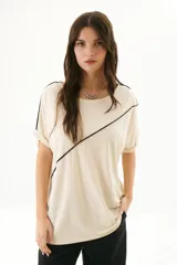 Remera negra de corte holgado con cuello redondo y mangas cortas con dobladillo. Presenta una línea diagonal blanca que cruza el frente desde el hombro hasta la cadera.