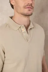 Remera tipo polo color beige, de manga corta y corte clásico. Tiene cuello con botones y está confeccionada en algodón.