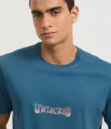 Remera celeste de algodón peruano, corte clásico, con cuello redondo y mangas cortas. Estampa frontal con la palabra "Unlocked" en letras plateadas con efecto 3D.