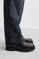 Bota negra de cuero con cordones, suela track y tirador trasero.