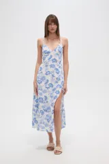Vestido largo confeccionado en viscosa con estampado floral azul sobre fondo blanco. Posee escote en V, tirantes finos, cintura elástica y una abertura lateral profunda en la falda.
