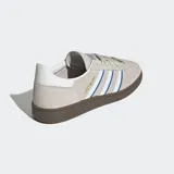 Championes de corte bajo color beige, con detalles de tres franjas en azul, suela de caucho natural y parte superior de gamuza sintética.