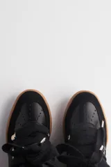 Zapatilla urbana negra de caña alta con plataforma, cordones y detalles de cuero y gamuza.