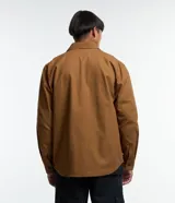 Camisa marrón de manga larga, confeccionada en sarga, con cuello inglés, abotonado delantero, bolsillos en el pecho con solapa y puños abotonados.