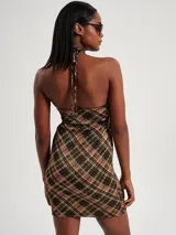 Vestido corto con estampado a cuadros en tonos marrón, verde y dorado. Diseño ajustado con cuello halter y espalda descubierta.