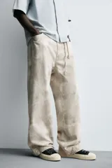 Pantalón de jean blanco, corte holgado y amplio en toda la pierna, tiro medio, tejido ligero, cinco bolsillos, efecto lavado y cierre frontal con cremallera y botón.