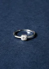 Anillo de plata 925 con diseño inspirado en el anillo de Lady Di. Presenta una piedra central redonda rodeada de zirconias en engarce cuadrado.