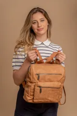 Mochila mediana de símil cuero color beige, con asa superior, dos compartimentos principales con cierre y dos bolsillos frontales con cierre. Las correas son ajustables y de color beige.