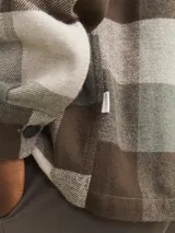 Sobrecamisa a cuadros marrón, beige y verde, de manga larga con cierre de botones y bolsillos en el pecho.