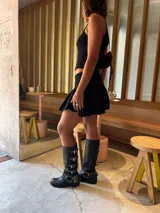 Botas de cuero gastado color marrón con hebillas y apliques de metal de caña alta.