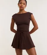 Short pollera color marrón de malla de algodón con cintura elástica y lazo ajustable. Prenda con buenas prácticas ambientales.