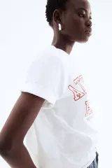 Remera blanca de algodón con estampado rojo que dice "Atelier Paris 115 Av. France, Paris".