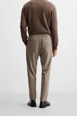 Pantalón color arena de corte recto, confeccionado en tejido elástico. Cuenta con cintura elástica ajustable con cordón, bolsillos laterales y bolsillos de vivo en la parte trasera.