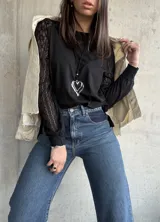 Remera negra de manga larga, con un hombro de tela de algodón y el otro de encaje.
