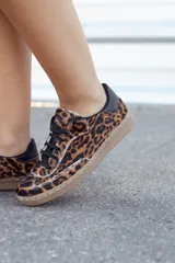 Zapatillas deportivas con estampado animal print de leopardo, cordones negros y suela color caramelo.