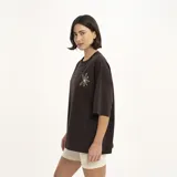 Remera manga corta color marrón con estampado de una flor dorada en el pecho.