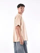 Remera gris de corte oversized, cuello redondo y mangas cortas. 
