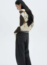 Sweater de punto color crema con diseño de rombos en marrón, gris y ocre. Tiene cuello en V y mangas largas con terminaciones en canalé.
