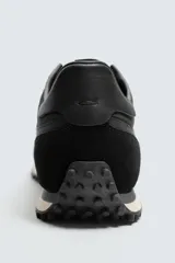 Zapatilla de cordones negra de estilo retro. Parte superior fabricada en tejido técnico y detalles en piel con acabado serraje. Suela dentada con detalle a contraste.