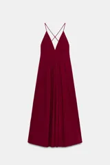 Vestido largo color vino tinto, con escote en V profundo y tirantes finos que se cruzan en la espalda. La falda es amplia y con caída.