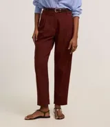 Pantalón zanahoria de cintura alta color borgoña, con trabillas, pliegues y cinturón fino de cuero sintético.