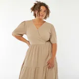 Vestido largo color beige de tejido gofrado, con escote cruzado en V, mangas cortas abullonadas y falda amplia con corte en capas.