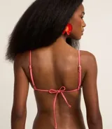 Top de bikini triangular fruncido color rosado, confeccionado en microfibra brillante. Tiene breteles ajustables y contorno de mini abalorios de madera.