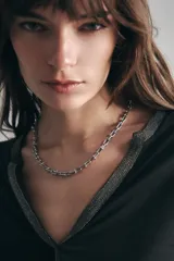 Collar de cadena plateada con eslabones anchos y alargados, con pequeños detalles esféricos en los puntos de unión.