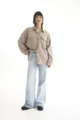 Camisa oversize color borgoña de pana con cuello camisero, cierre frontal con botones, dos bolsillos con solapa en el pecho y mangas largas con puños abotonados.