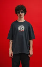 Remera de algodón premium color carbón, corte oversize, con cuello redondo y manga corta. Presenta un estampado frontal con calaveras en estilo caricaturesco, una de ellas con sombrero de copa, rodeadas de humo o nubes, y el texto "CHILLED THE BONE".