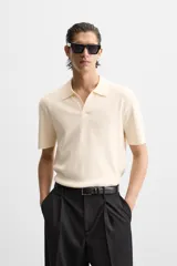 Polo color crema de punto, corte regular fit, cuello solapa con abertura frontal y manga corta.