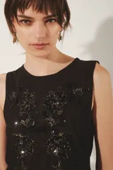 Top negro sin mangas confeccionado en mesh con bordado de flores a tono.