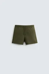 Bañador corto color verde militar confeccionado en tejido técnico. Cuenta con cintura elástica ajustable con cordón, bolsillos laterales, bolsillo trasero de vivo y forro interior.