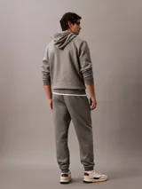 Pantalón de jogging gris con cintura elástica, bolsillos laterales y logo de Calvin Klein Jeans en la pierna. Confeccionado en mezcla de algodón y poliéster.