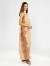Vestido largo color beige con estampado de girasoles marrones, corte holgado, cuello halter y espalda descubierta.