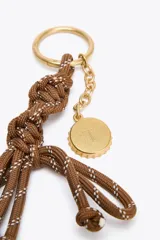 Charm para bolso con cuerda anudada color marrón y abalorios metálicos dorados.