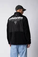 Campera negra con la parte superior de tela tipo rompevientos con dos bolsillos con solapa y la parte inferior de micro polar. Tiene cierre frontal y cuello alto.