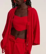 Kimono alargado color rojo, confeccionado en viscosa y lino. Tiene mangas largas y abertura frontal total con detalle de cuerdas dobles.