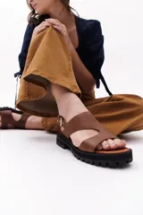 Sandalias marrones de cuero con suela track negra y hebilla plateada.