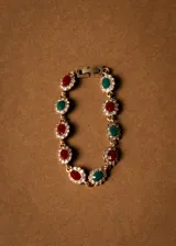 Pulsera dorada con eslabones de bronce y cristales rojos, verdes y blancos engarzados en forma floral.