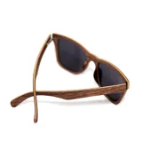Lentes de sol con marco cuadrado de madera color marrón claro y lentes negros.