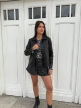 Chaqueta plateada metalizada con cuello camisero, cierre frontal con botones, bolsillos de parche en el pecho y corte recto.