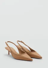 Zapato destalonado color beige con punta fina, detalle de tachuelas y cierre de hebilla. El tacón mide 4,5 cm.