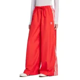 Pantalón Adidas rojo de corte ancho con cintura elástica ajustable con cordón y logo de la marca bordado en blanco. Presenta las tres líneas características de Adidas en color blanco a lo largo de las piernas.