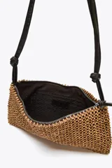 Bolso de hombro con cuerpo de abalorios color madera y asa de cuero sintético marrón con detalle de nudos. Tiene un bolsillo interior y cierre con cremallera metálica.