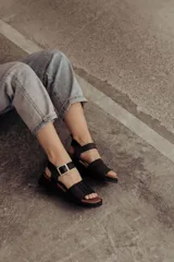 Sandalias bajas color arena, con tiras anchas de cuero y hebilla lateral.